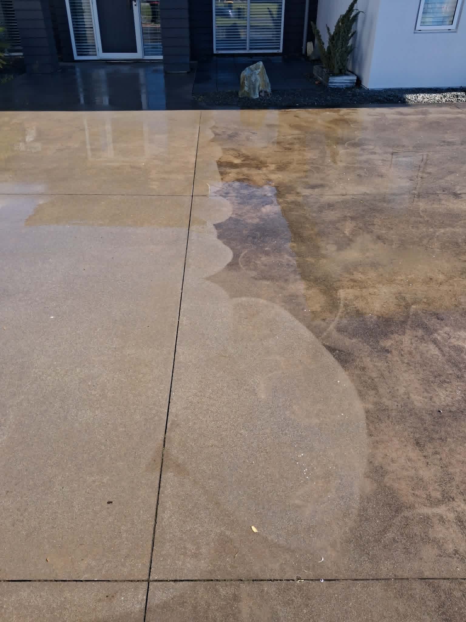 Driveway being restored, showing a sharp line between dirty and cleaned concrete